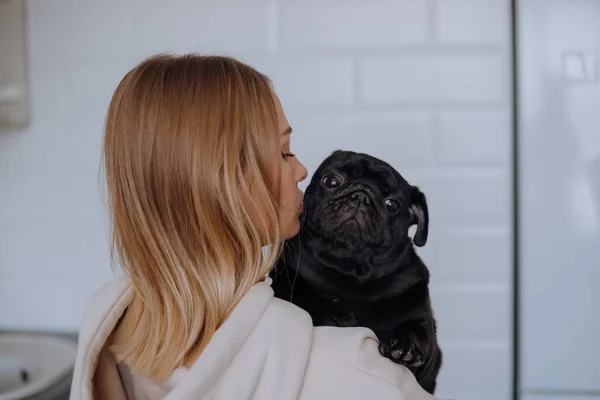 Portrait of a black pug dog, and a blonde girl with blue eyes — Stock Photo, Image