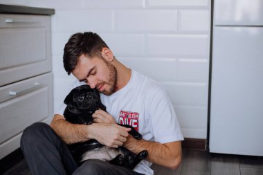 Adam bir köpeğe nazikçe sarılıyor.
