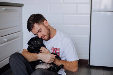 Adam bir köpeğe nazikçe sarılıyor.