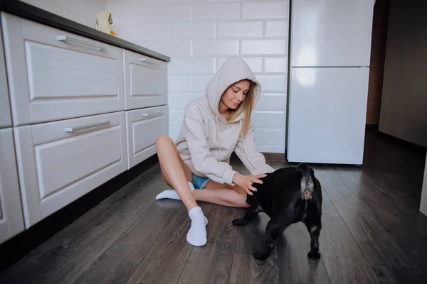 Fille jouer avec un chien carlin noir sur le sol — Photo