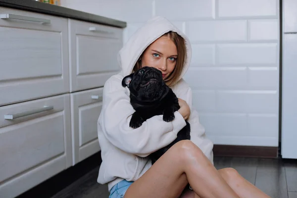 소녀가 집에서 검은 개를 품에 안고 있다 — 스톡 사진