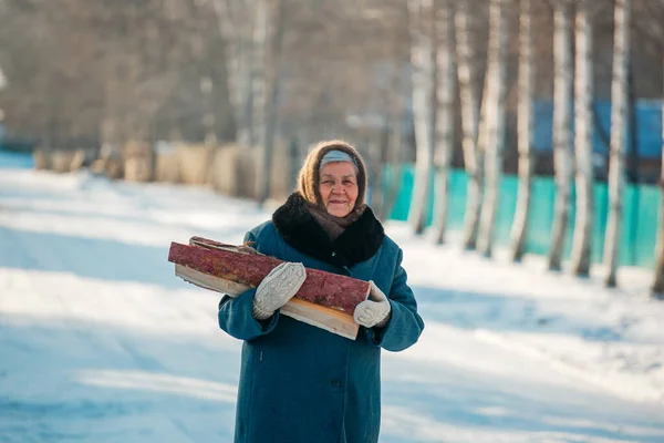 Портрет русской бабушки, в деревне зимой, готовящей дрова, в Сибири — стоковое фото