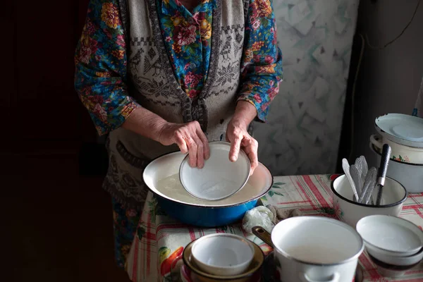 La nonna russa lava piatti in un bacino nel villaggio — Foto Stock