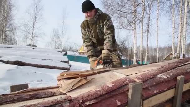Seorang penebang menebang pohon di hutan pada musim dingin, di Rusia untuk mencari kayu bakar — Stok Video