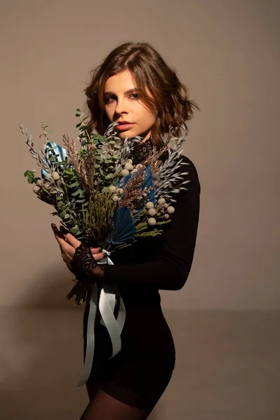Retrato de una mujer morena en un estudio fotográfico, con un ramo de flores secas —  Fotos de Stock