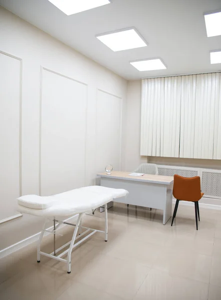 Intérieur moderne du bureau de cosmétologie avec un lit et une chaise de beauté faciale entièrement électriques, et étagères avec des produits de soins de la peau dans un salon de beauté. — Photo