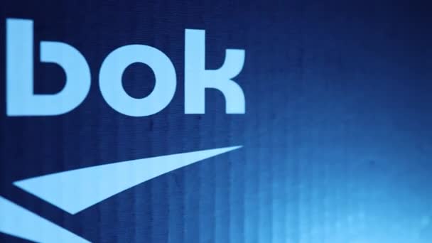 Reebok logo, op een blauwe achtergrond in neon licht — Stockvideo