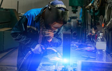 Kaynakçı yarı otomatik kaynak makinesinde elektrot ile çalışıyor..