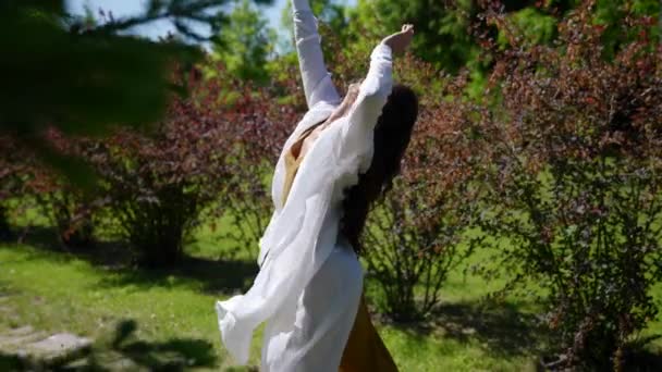 在公园里，年轻的亚洲女人张开双臂旋转着 — 图库视频影像
