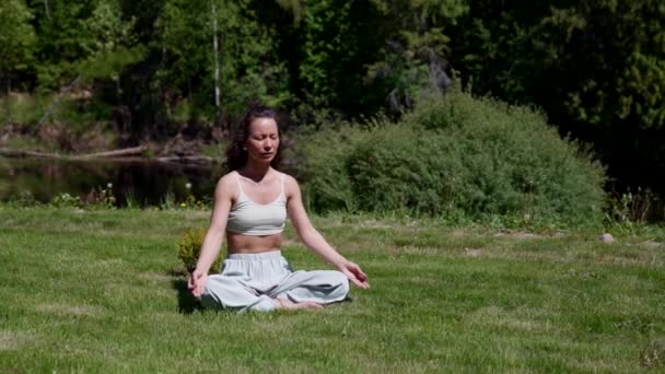 Femme mince en position lotus pratique la méditation et la relaxation dans le parc — Video
