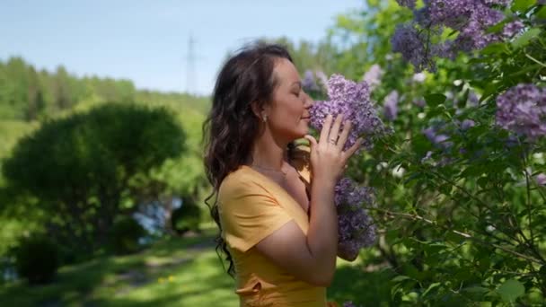 Eine glückliche Frau genießt einen Spaziergang in der Natur und inhaliert den Duft von Frühlingsblumen — Stockvideo