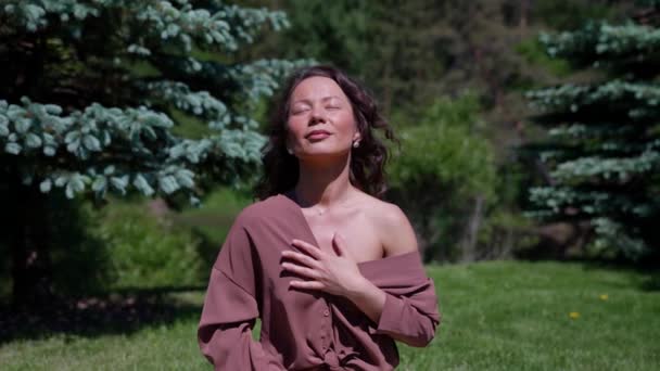 Een Aziatische vrouw beoefent yoga en mediteert in een lotuspositie in een park. Gezond meisje zittend in de lotuspositie, mediterend of yoga beoefenend in de natuur, buiten — Stockvideo