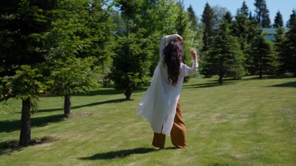 トランス状態の公園で白いケープダンスの女性が即興で踊る — ストック動画