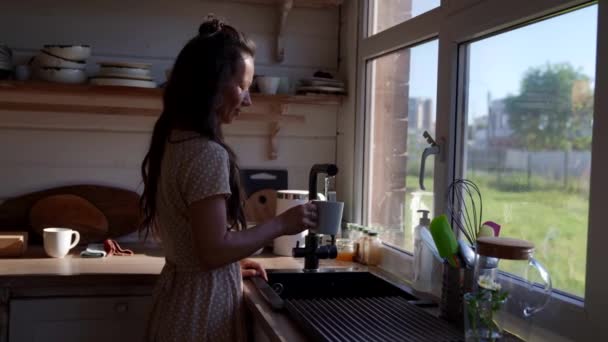 Žena nalévá čistou filtrovanou vodu z kohoutku do sklenice v kuchyni — Stock video