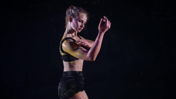 Стройная женщина танцует в черной студии с краской на теле — стоковое видео