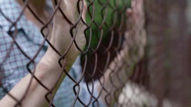 Metal bir çitin arkasında hapisteki bir kadının yakın çekimi.