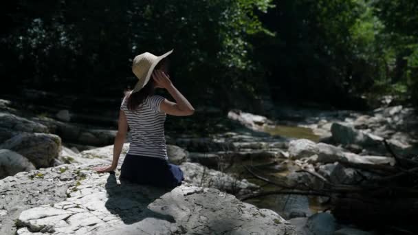Μια λεπτή γυναίκα αναπαύεται στο δάσος δίπλα σε ένα ποτάμι του βουνού μια ηλιόλουστη καλοκαιρινή μέρα — Αρχείο Βίντεο