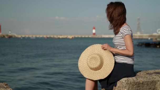 Uma mulher triste está sentada à beira-mar no porto olhando para a distância pensando — Vídeo de Stock