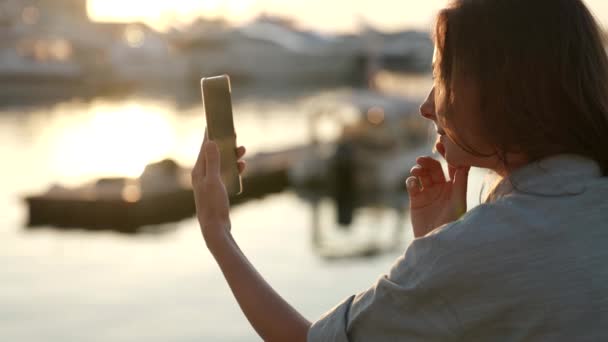 해 가 저물어 가는 여자의 모습 스마트폰으로 영상 통화를 하는 모습. 무선 기술 사용 자의 현대적 인 개념. — 비디오