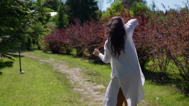 Una hippie bailando en un campo con flores. Una mujer en el estilo boho en el contexto de la naturaleza — Vídeo de stock