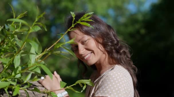 Retrato de uma mulher linda em um passeio no parque em uma manhã ensolarada. Uma beleza com cabelos longos soltos goza de férias — Vídeo de Stock