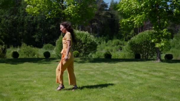 休暇を楽しむ屋外の緑の庭を歩く全体の若い女性 — ストック動画