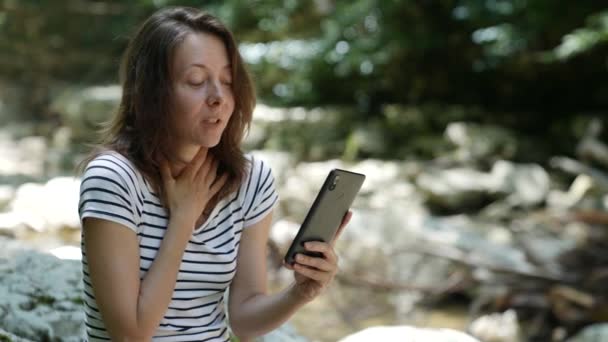 Portrét šťastné ženy, jak mluví na videu s mobilním telefonem pod širým nebem. Usmívající se dáma drží venku v rukou mobilní telefon.. — Stock video