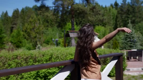 Eine junge Frau tanzt verträumt auf der Veranda eines Landhauses — Stockvideo