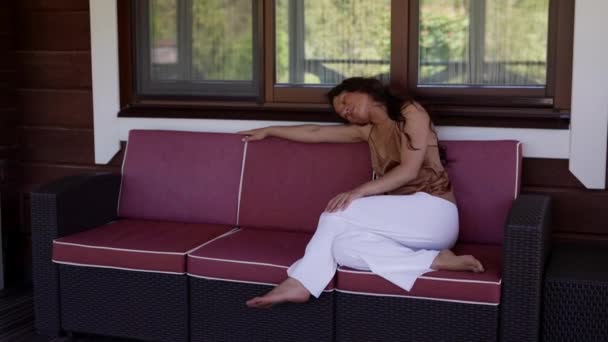 Une jeune femme blanche calme et belle se détendant dans un canapé confortable à l'intérieur, profitant d'un week-end calme sans stress, méditant un à la maison. — Video