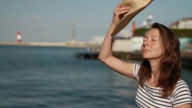 Deniz kenarında tatilde olan orta yaşlı bir kadın sabah güneşinin büyük bir şapka takmasından hoşlanıyor.