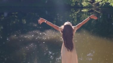 Hippi bir kadın kamp parkında altın güneş ışınlarında dans ederek sabahının tadını çıkarıyor. Neşeli genç bir kadın mutlu anının tadını çıkarır.