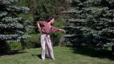 Genç bir kadın doğanın tadını çıkarıyor, rahatlıyor, özgürlük kavramı güzel bir Asyalı kız çimenlerin üzerinde mutlu bir şekilde dans ediyor.