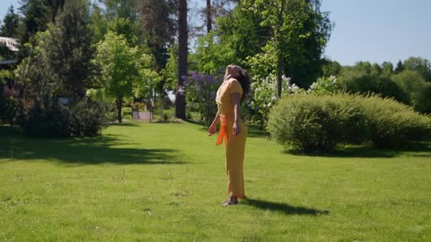 Uma jovem de cabelos longos feliz está dançando na natureza apreciando o calor do sol de verão — Vídeo de Stock