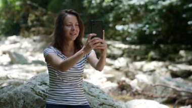 Yetişkin bir kadın cep telefonuyla video iletişimiyle konuşuyor. Akıllı telefonu olan odaklanmış bir hippi kadın..