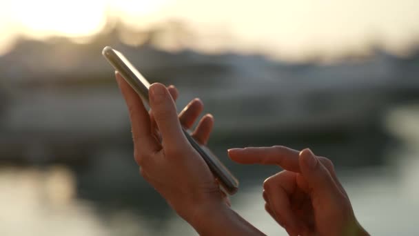 Închiderea utilizării unui telefon mobil pentru a trimite un mesaj în soarele apusului în razele degetelor blânde de sex feminin — Videoclip de stoc