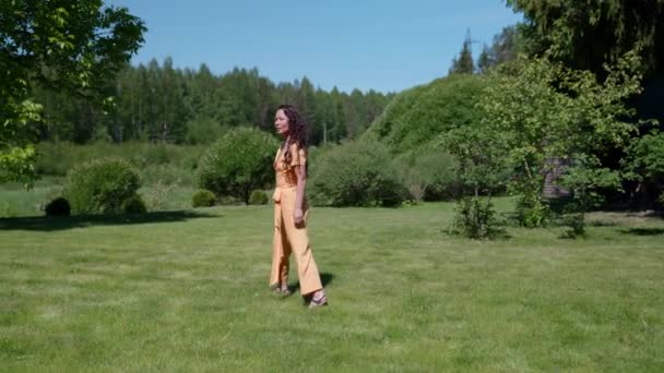 Hermosa mujer hippie caminando a través de un parque verde al atardecer con hermoso pelo largo dorado — Vídeos de Stock