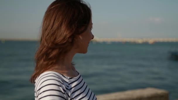 Slow motion portrait of an adult woman enjoying inhaling the smell of the sea while standing on the shore — Stock Video