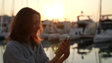 Güzel hippi kadın sahilde telefonuyla yürüyor ve internette video konferansları düzenliyor.