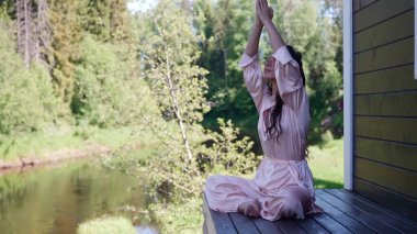 Nilüfer pozisyonunda alternatif tıp dalında nefes alma pratiği yapan kadın, doğada sağlığını geri kazanıyor.