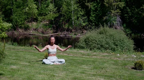 Азиатская женщина закрыла глаза и делает позу йоги Намасте. Девушка выполняет йогу асана во время медитации в парке на зеленой траве. Успокойся и расслабься. — стоковое фото