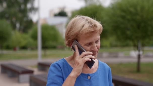 Portret van een gelukkige gepensioneerde een vrouw is praten aan de telefoon op straat — Stockvideo