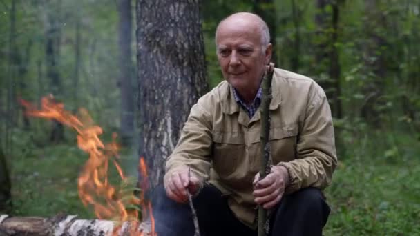 A retired tourist sits in the forest by the fire and reflects on the days he has lived — Stock Video