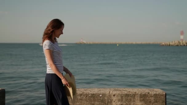 Slanke volwassen vrouw wandelen langs de zee dijk in de middag bij zonnig weer — Stockvideo