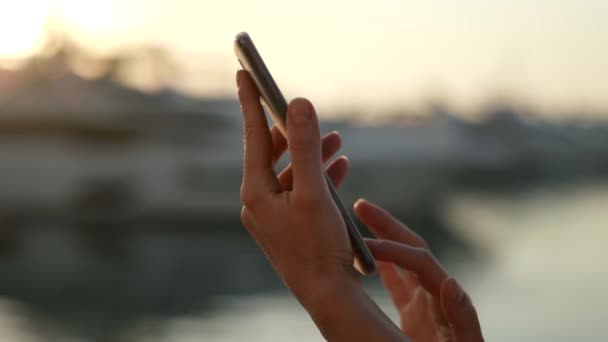 Close-up de mulheres mãos lançando através da tela sensível ao toque de um telefone celular na rua — Vídeo de Stock