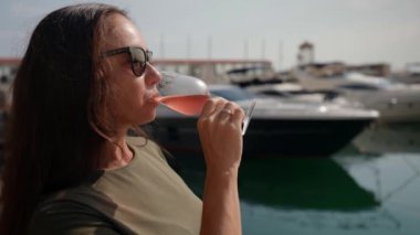 Tatil sırasında elinde bir bardak nefis pembe şampanyayla aydınlık elli zengin bir kadın.