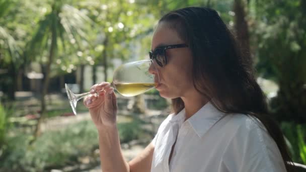 Успешная женщина наслаждается вкусом белого вина в течение дня в ресторане во время отдыха на курорте — стоковое видео