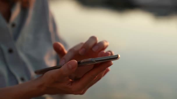 Close-up dari tangan perempuan alami memegang telepon modern dengan layar sentuh untuk akses internet — Stok Video