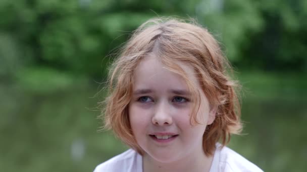 Portret van een slordig tienermeisje met slordig haar en een vies gezicht staat en probeert te glimlachen — Stockvideo