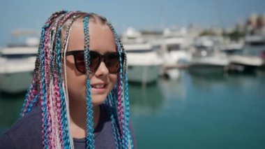 Akşamüstü gözlüklü, saçlarında örgü örgü saçlarıyla tatil köyünde son moda bir genç.