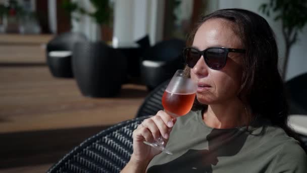 Une femme dans une main éclairée avec un verre de champagne exquis tout en se relaxant sur la terrasse d'un café extérieur par une journée ensoleillée — Video